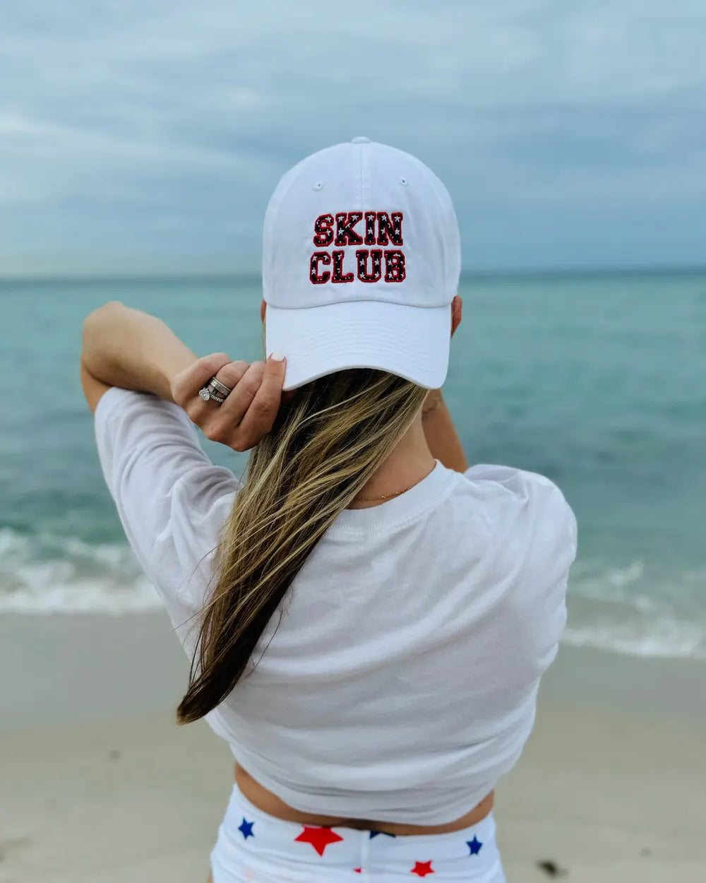 White Skin Club dad hat with star-print lettering, worn at the beach